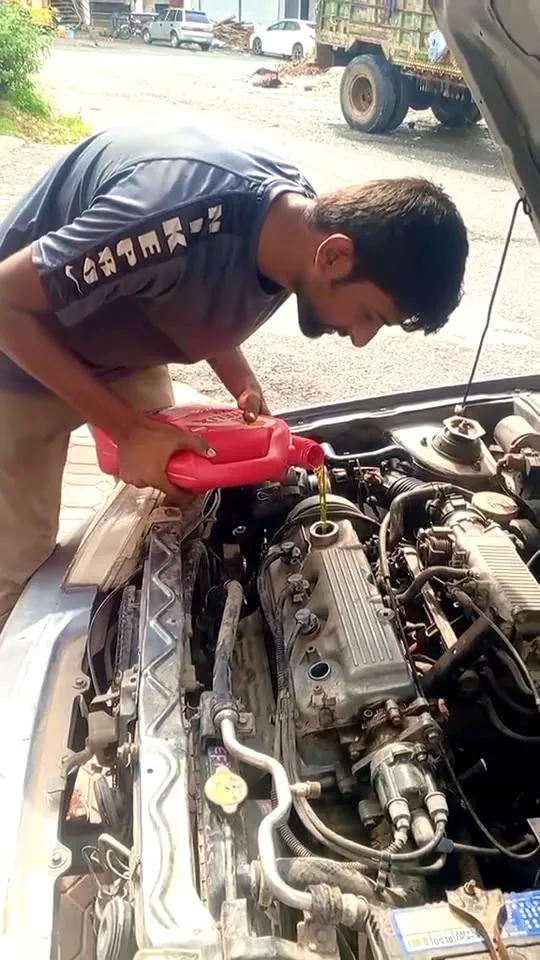 A mechanic leaning into the engine bay of a Suzuki Cultus